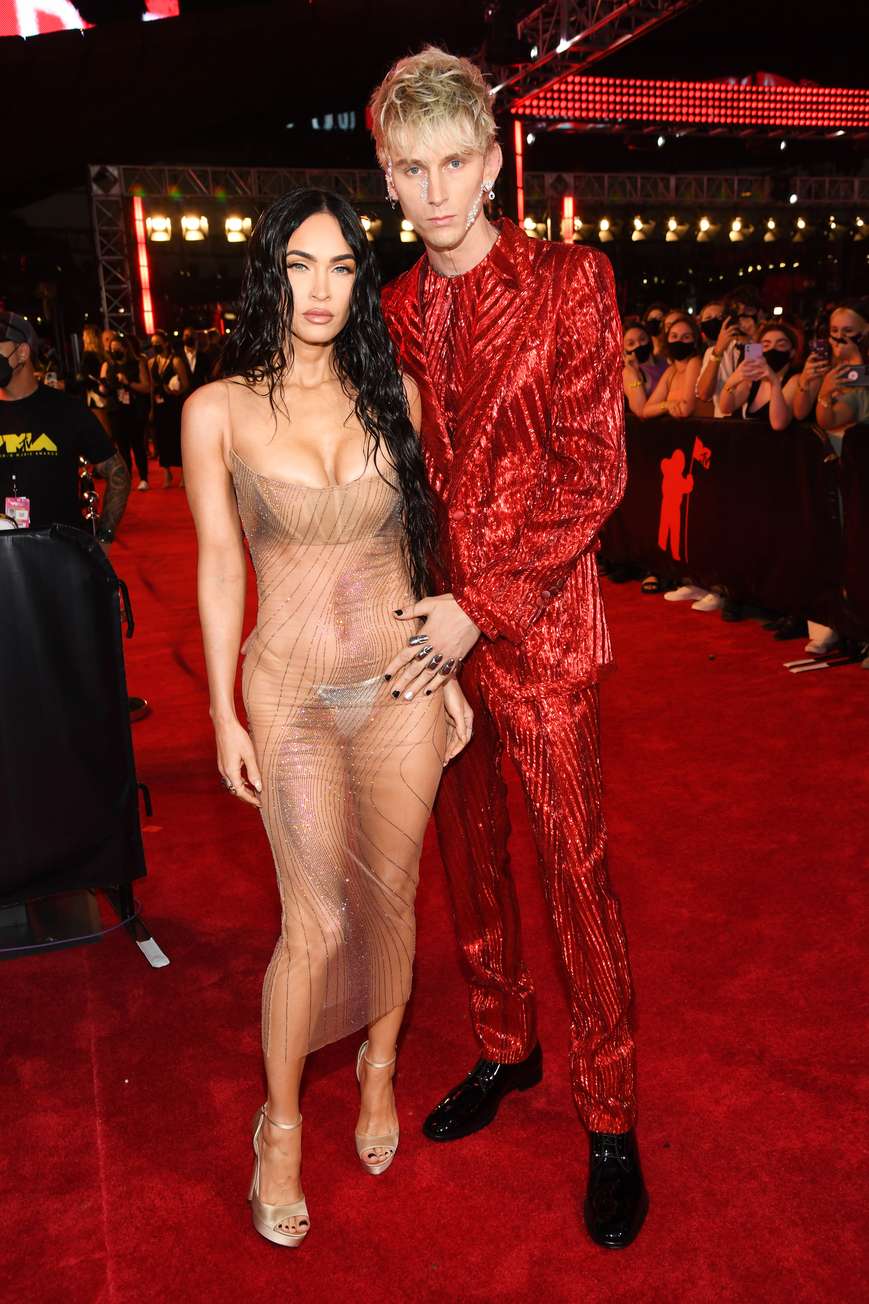 The pair posing on the red carpet, Megan in a sheer, figure-hugging dress and MGK in a shiny, textured suit