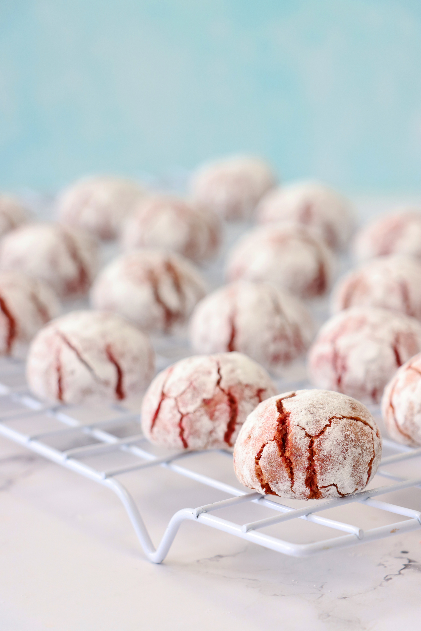 Freshly baked crinkle cookies on a wire rack, with powdered sugar coating