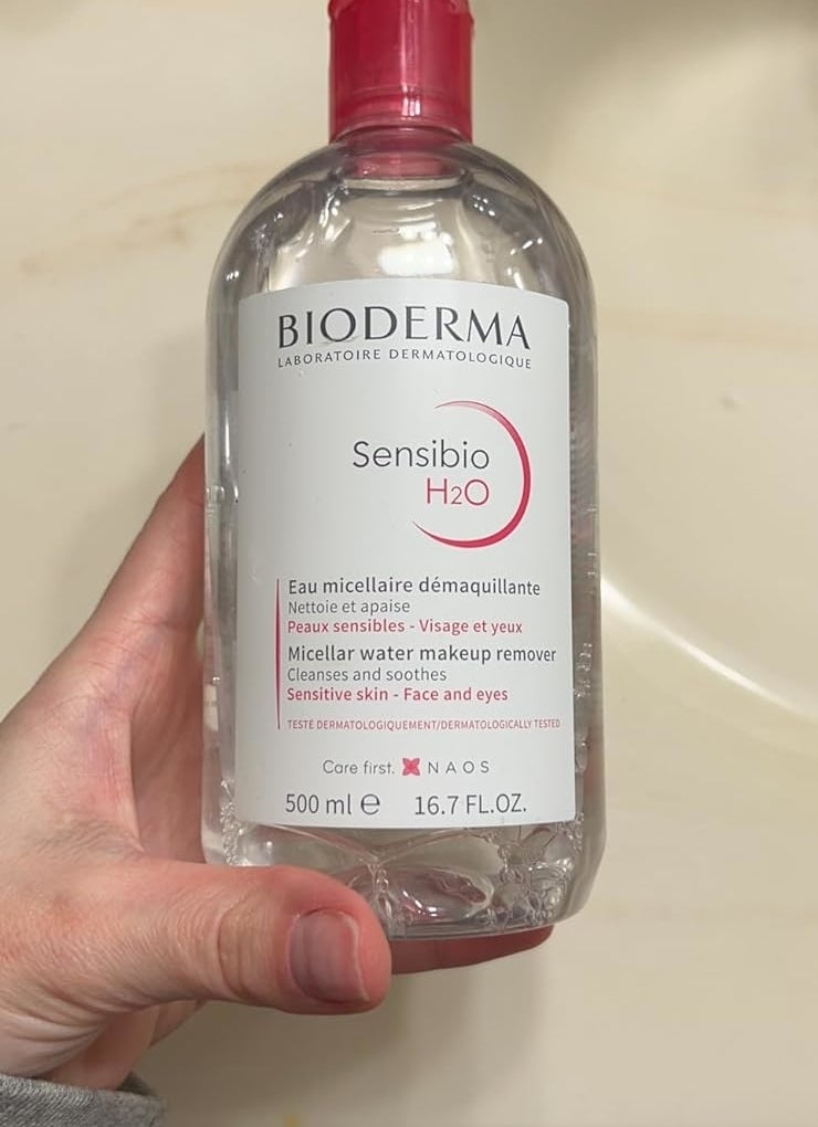 Hand holding Bioderma Sensibio H2O micellar water bottle, a makeup remover