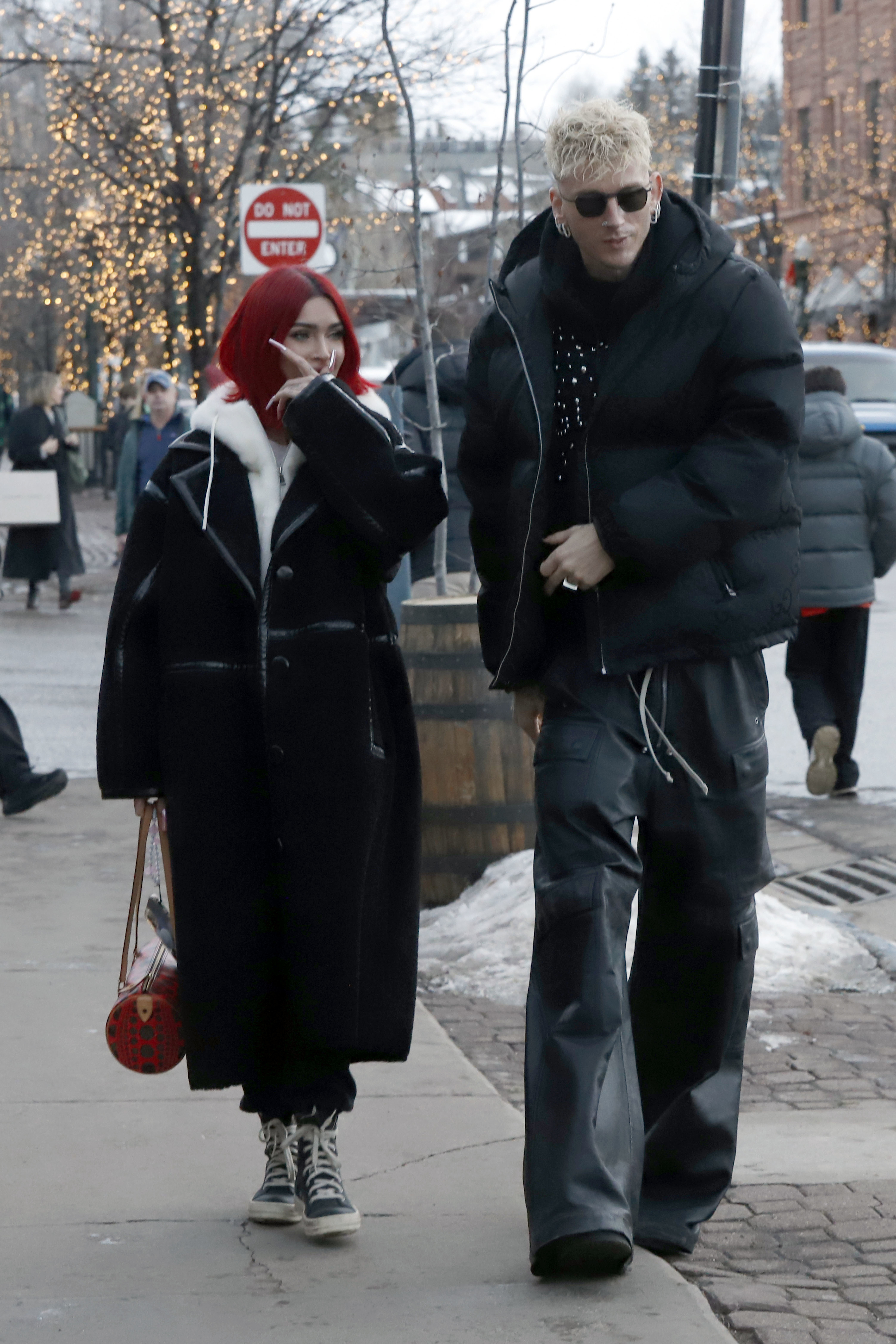 Megan in a long coat with a trim walking on the street with MGK who&#x27;s wearing a puffy jacket and sunglasses