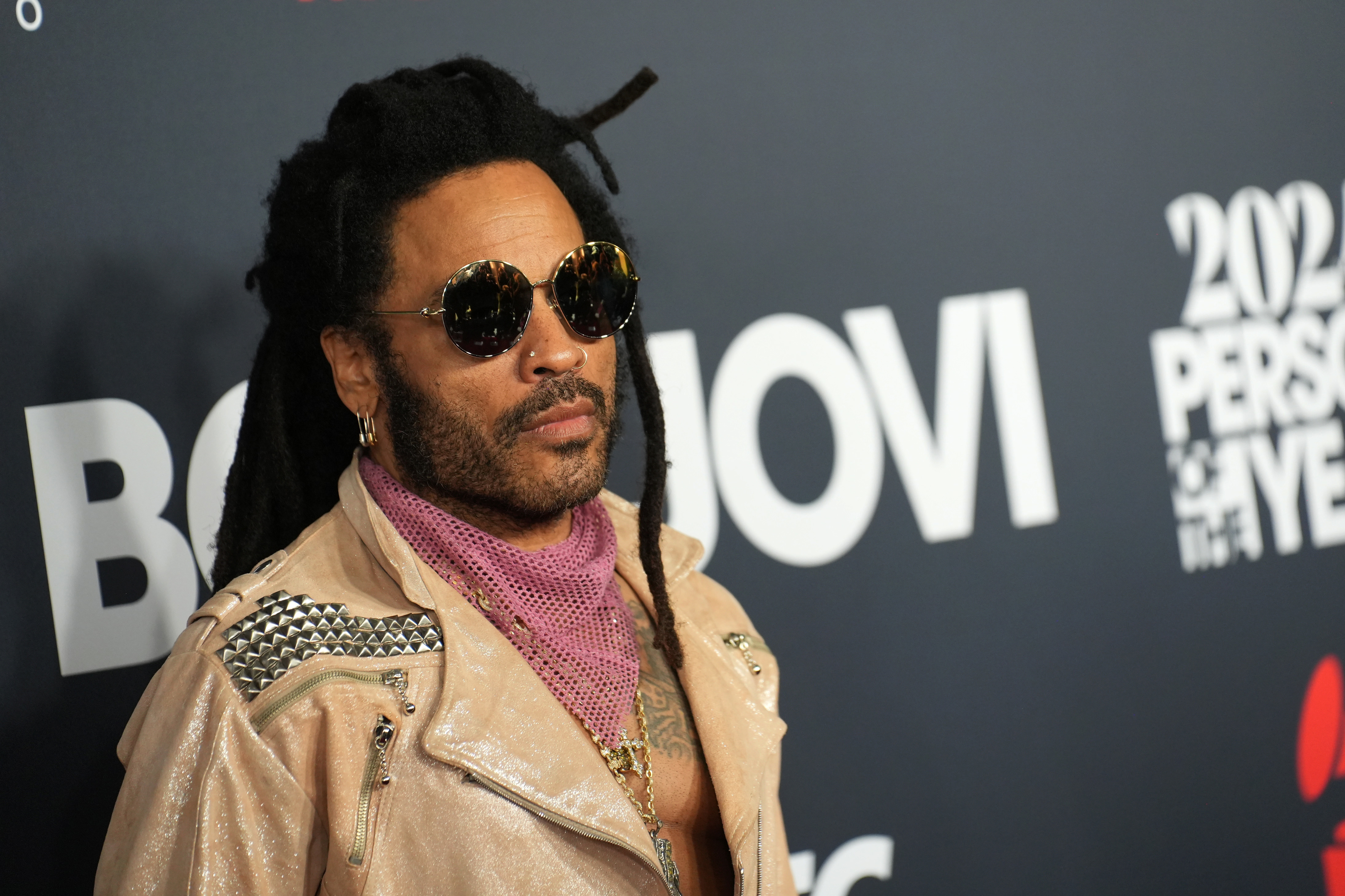 Closeup of Lenny Kravitz on the red carpet wearing round sunglasses