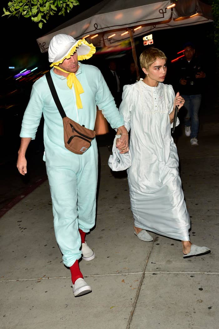 Two individuals walking, one in a duck costume and one in a white vintage dress with ruffles