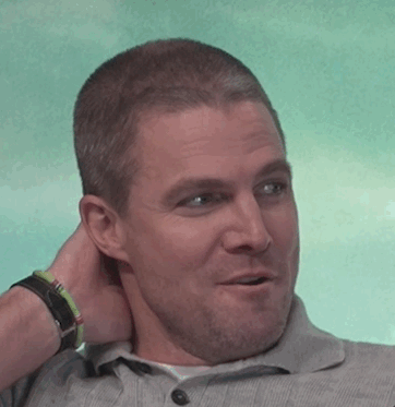 Man smiling and scratching his head, wearing a collared shirt and watch