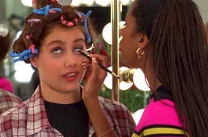 Cher Horowitz getting makeup applied, hair in rollers, in a scene from "Clueless"