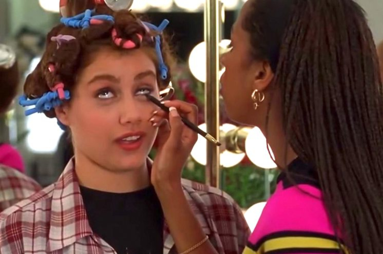 Cher Horowitz getting makeup applied, hair in rollers, in a scene from "Clueless"