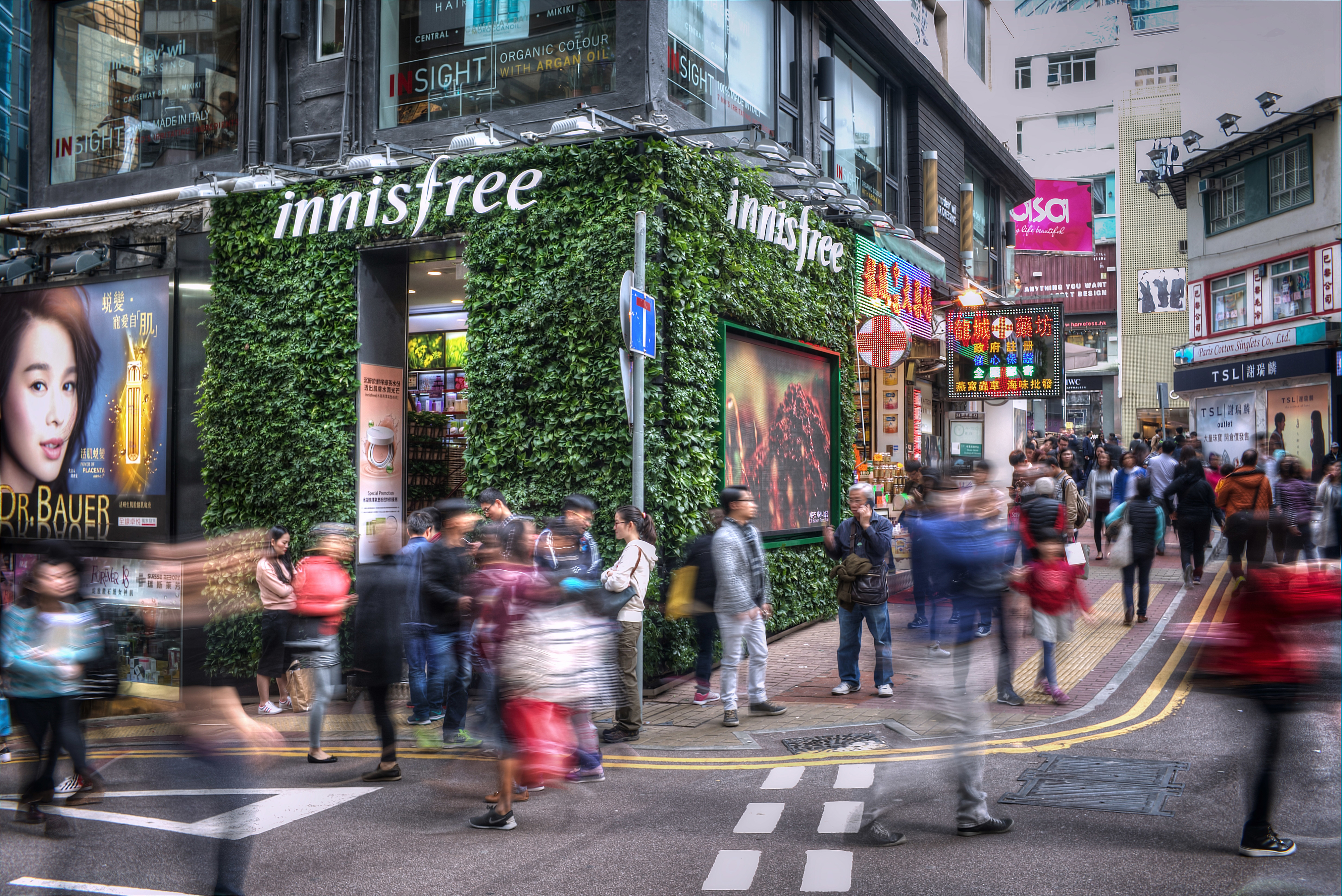 Busy street corner with blurred pedestrians and shop signs, capturing the lively atmosphere of urban travel