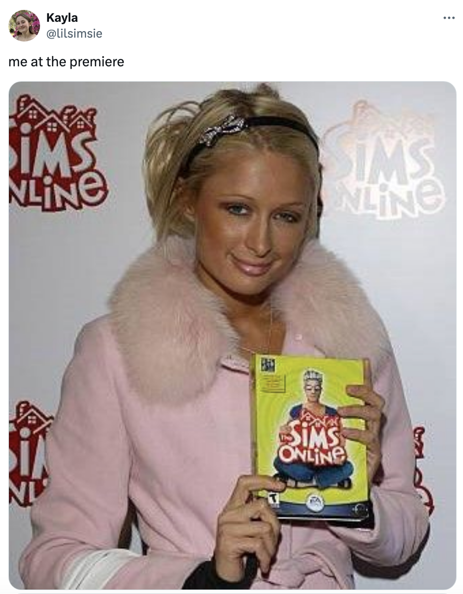 Paris Hilton in a jacket with fur collar holding The Sims Online game box at a premiere