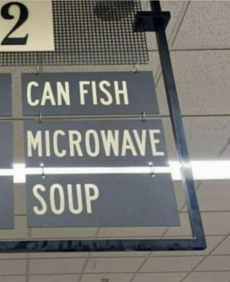 Store sign with items listed: &quot;CAN FISH,&quot; &quot;MICROWAVE,&quot; and &quot;SOUP&quot; in separate lines
