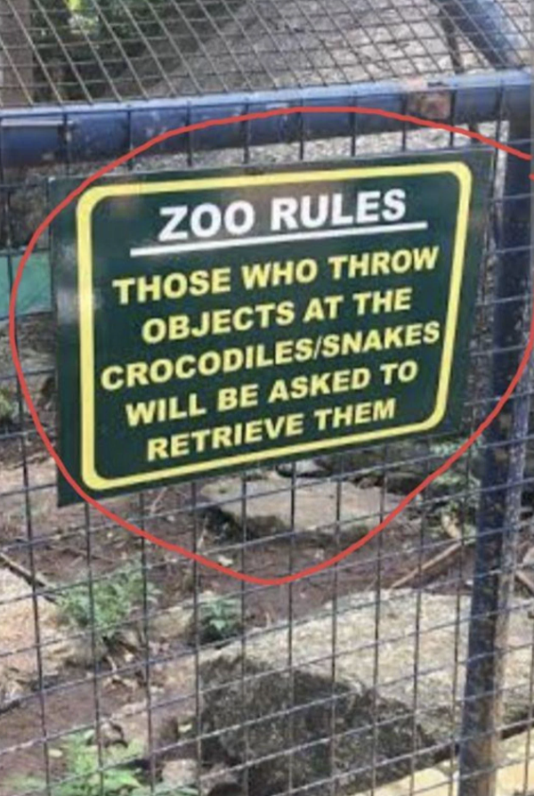 Sign reads &quot;ZOO RULES THOSE WHO THROW OBJECTS AT THE CROCODILES/SNAKES WILL BE ASKED TO RETRIEVE THEM&quot; with a red circle around it