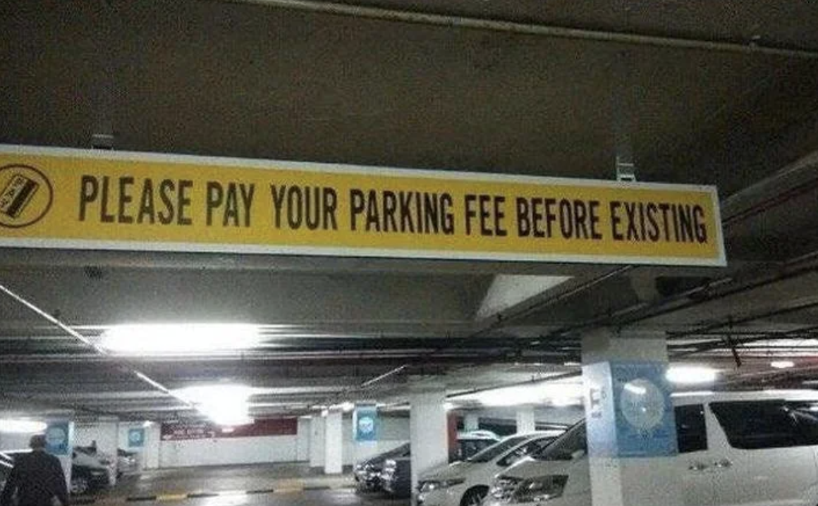 Sign in parking garage reads &quot;Please pay your parking fee before existing,&quot; likely meaning &quot;exiting.&quot;