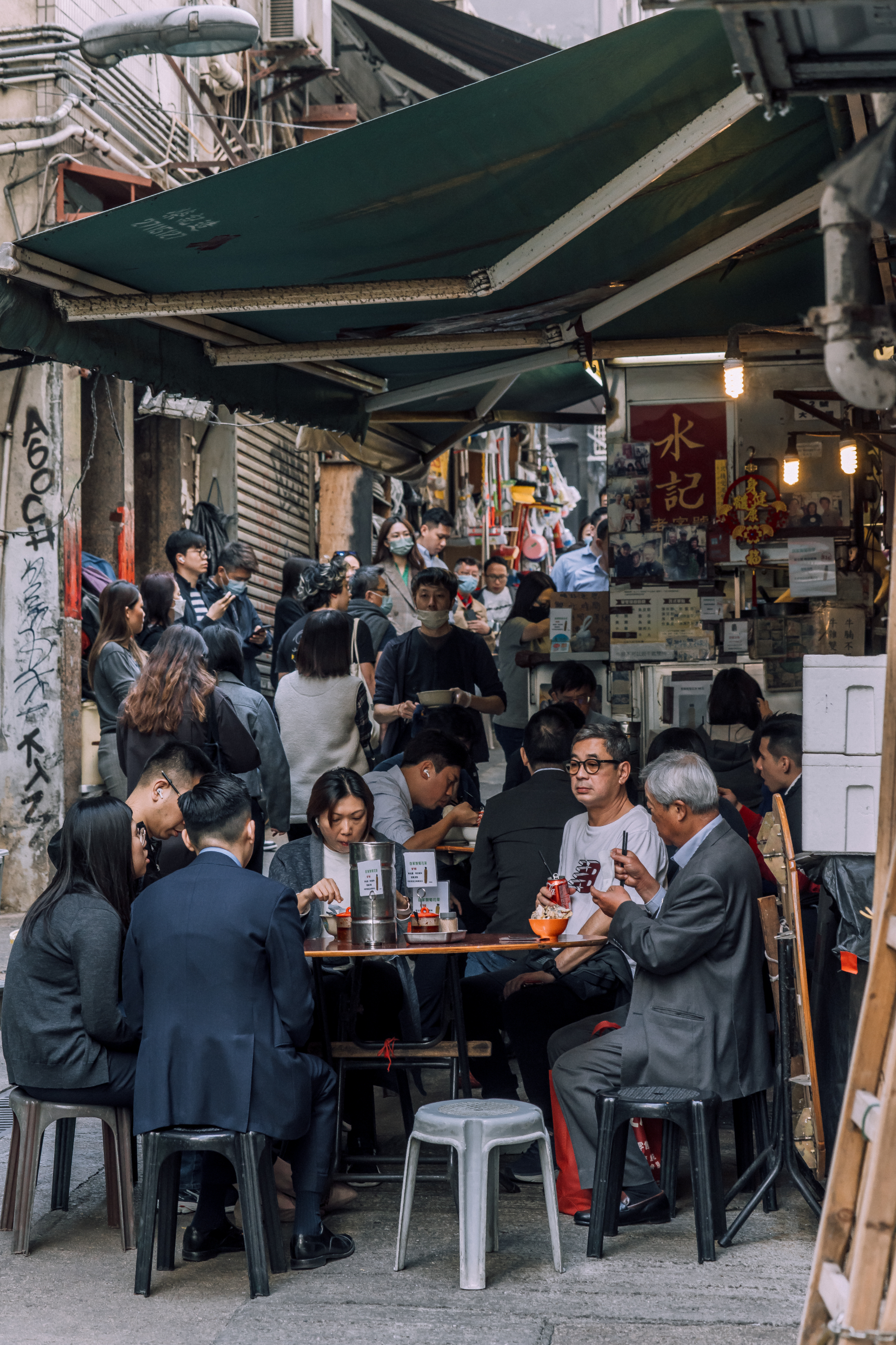 People dining at outdoor tables in a bustling street market
