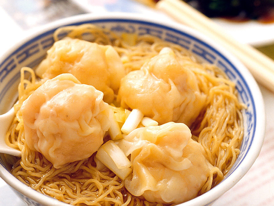 A bowl of wonton noodles with chopsticks resting on top