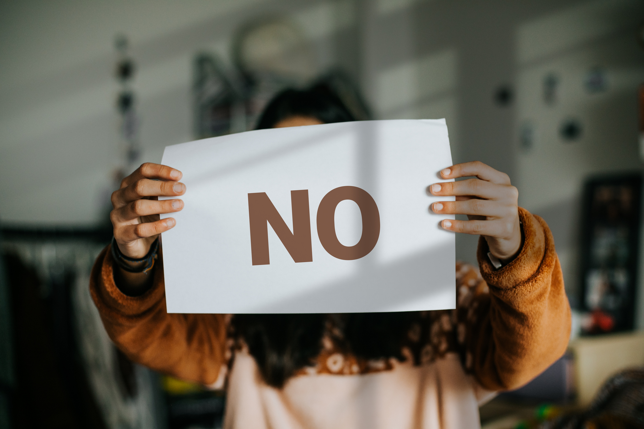 Person holding sign with &quot;NO&quot; in front of their face