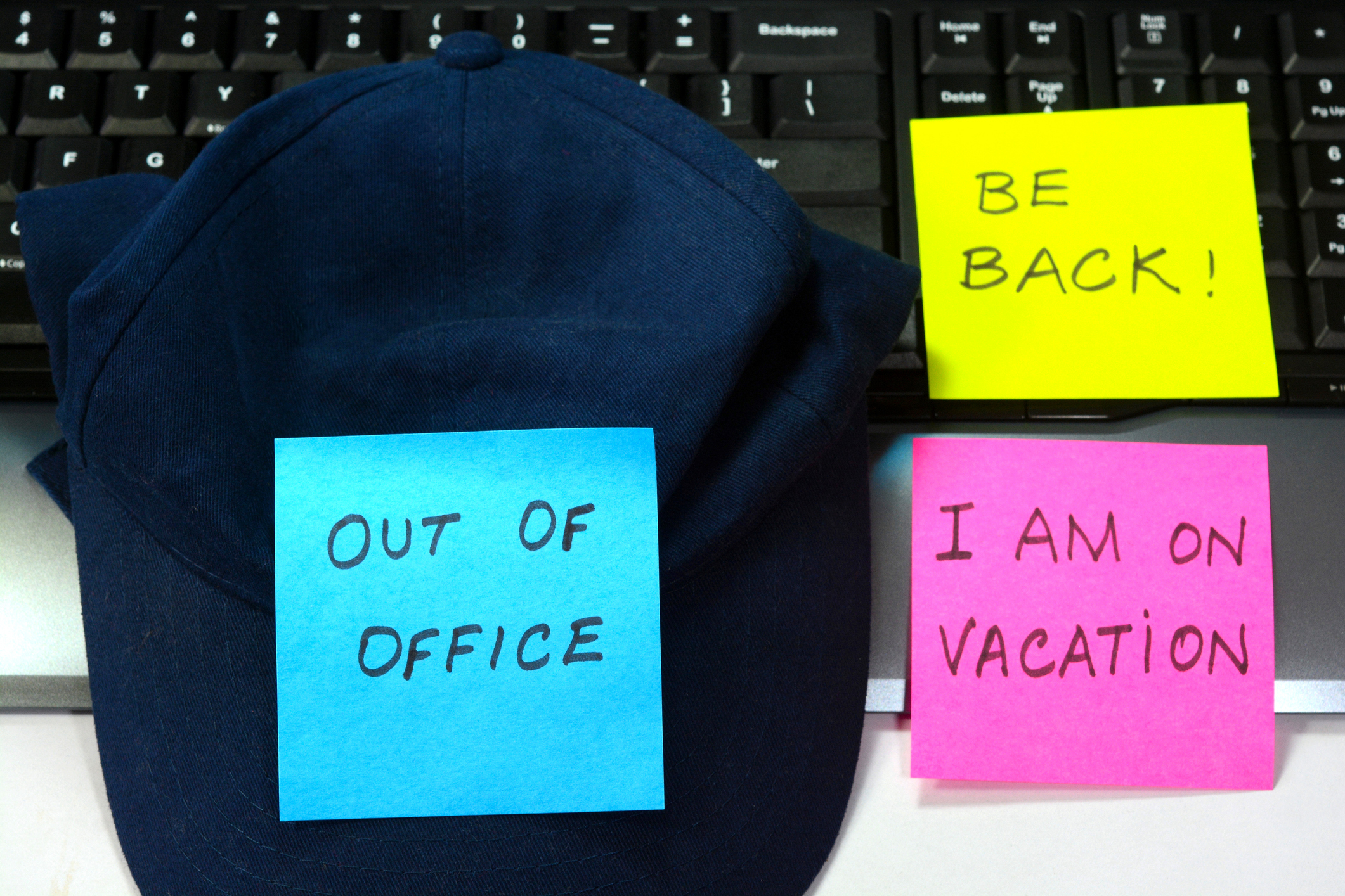 A cap with sticky notes saying &quot;OUT OF OFFICE&quot;, &quot;BE BACK!&quot; and &quot;I AM ON VACATION&quot; as a humorous out-of-office message