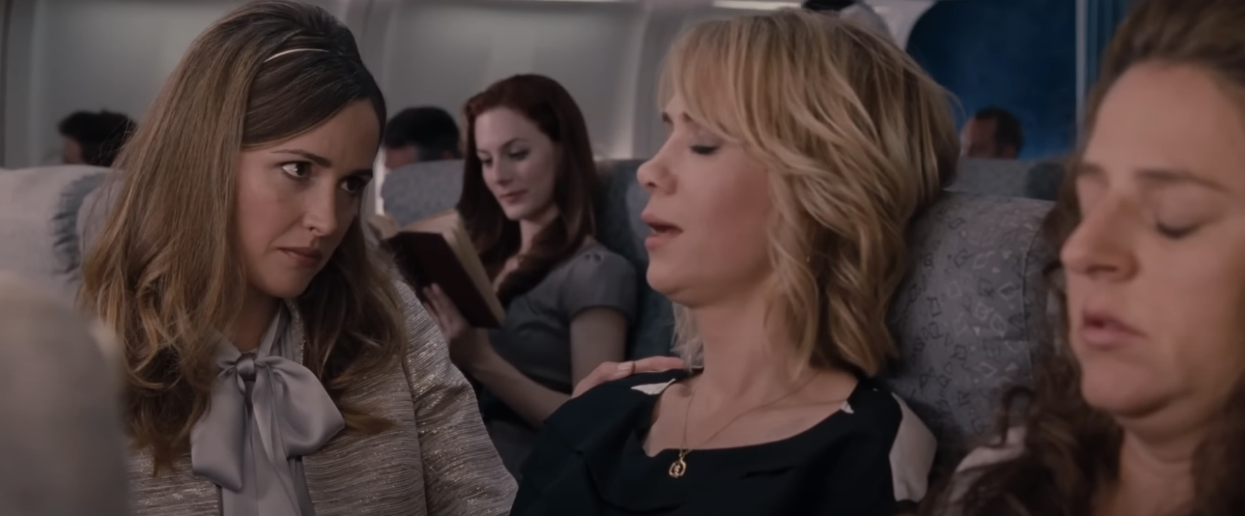 Characters from the film &quot;Bridesmaids&quot; seated on a plane with humorously distraught expressions