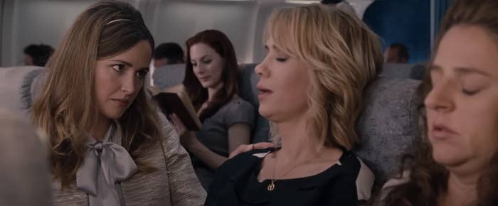 Characters from the film &#x27;Bridesmaids&#x27; seated on a plane, creating humorous expressions