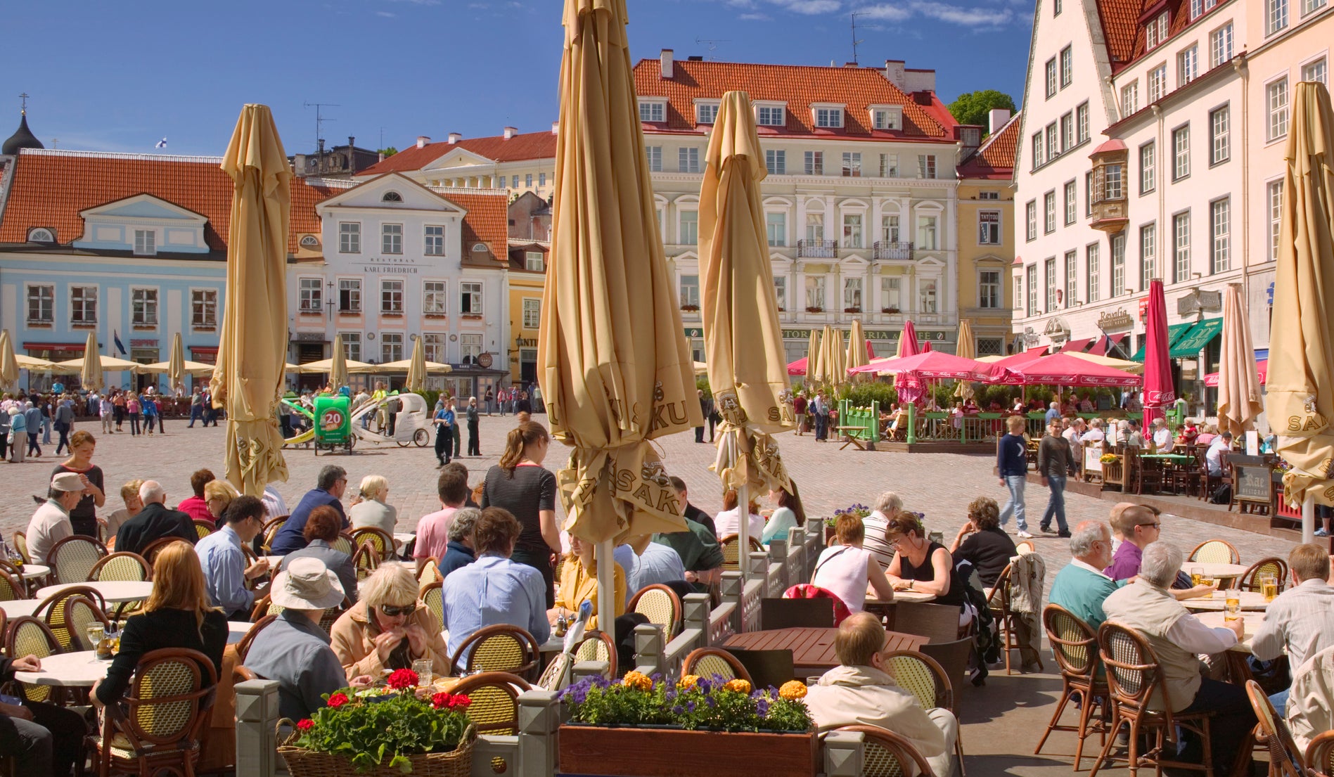 Outdoor café with people seated under umbrellas in a sunny town square