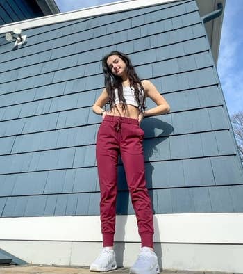 Person in casual cropped top and high-waisted pants with sneakers, posing outdoors