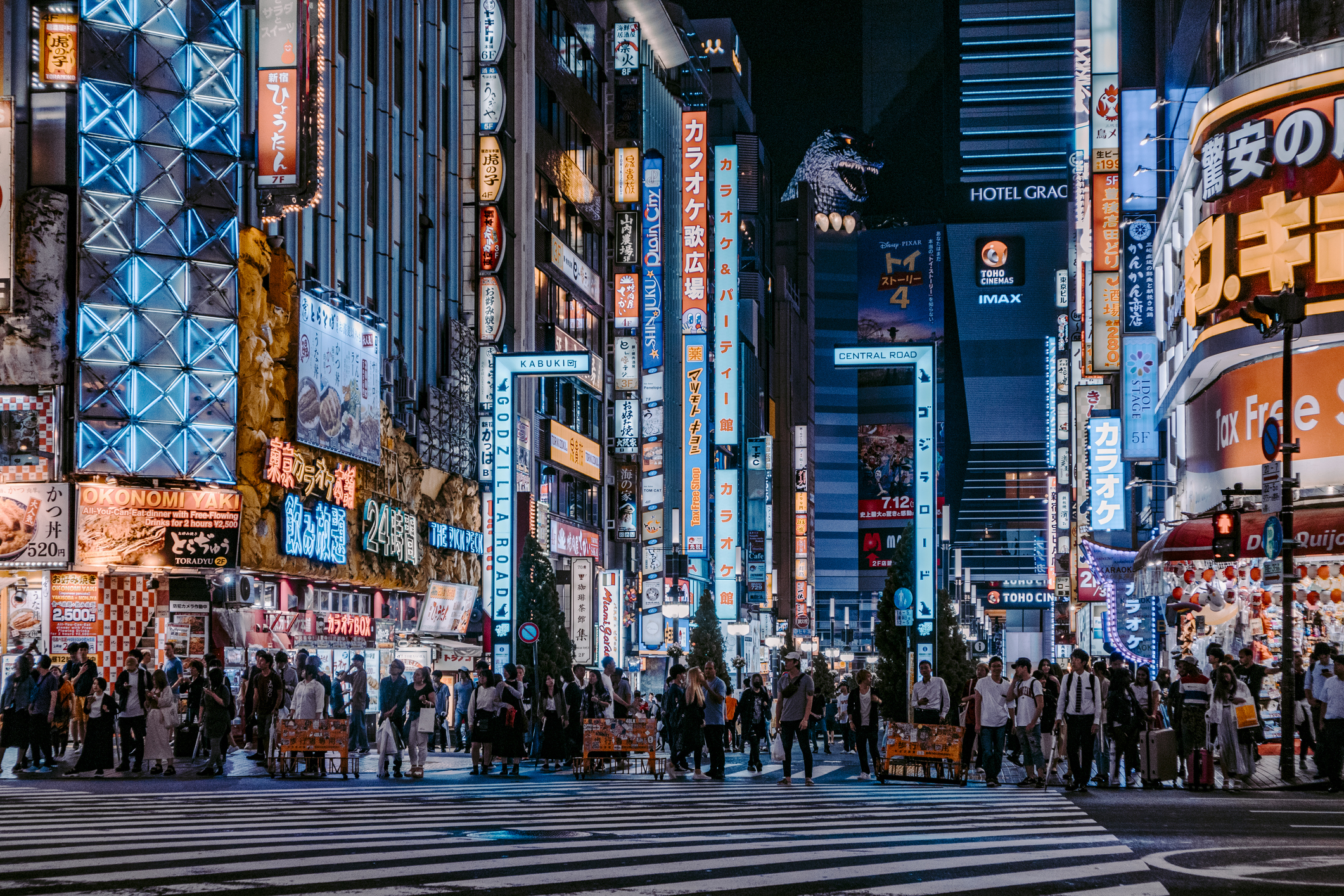 Crowded city street at night with neon signs and pedestrians crossing