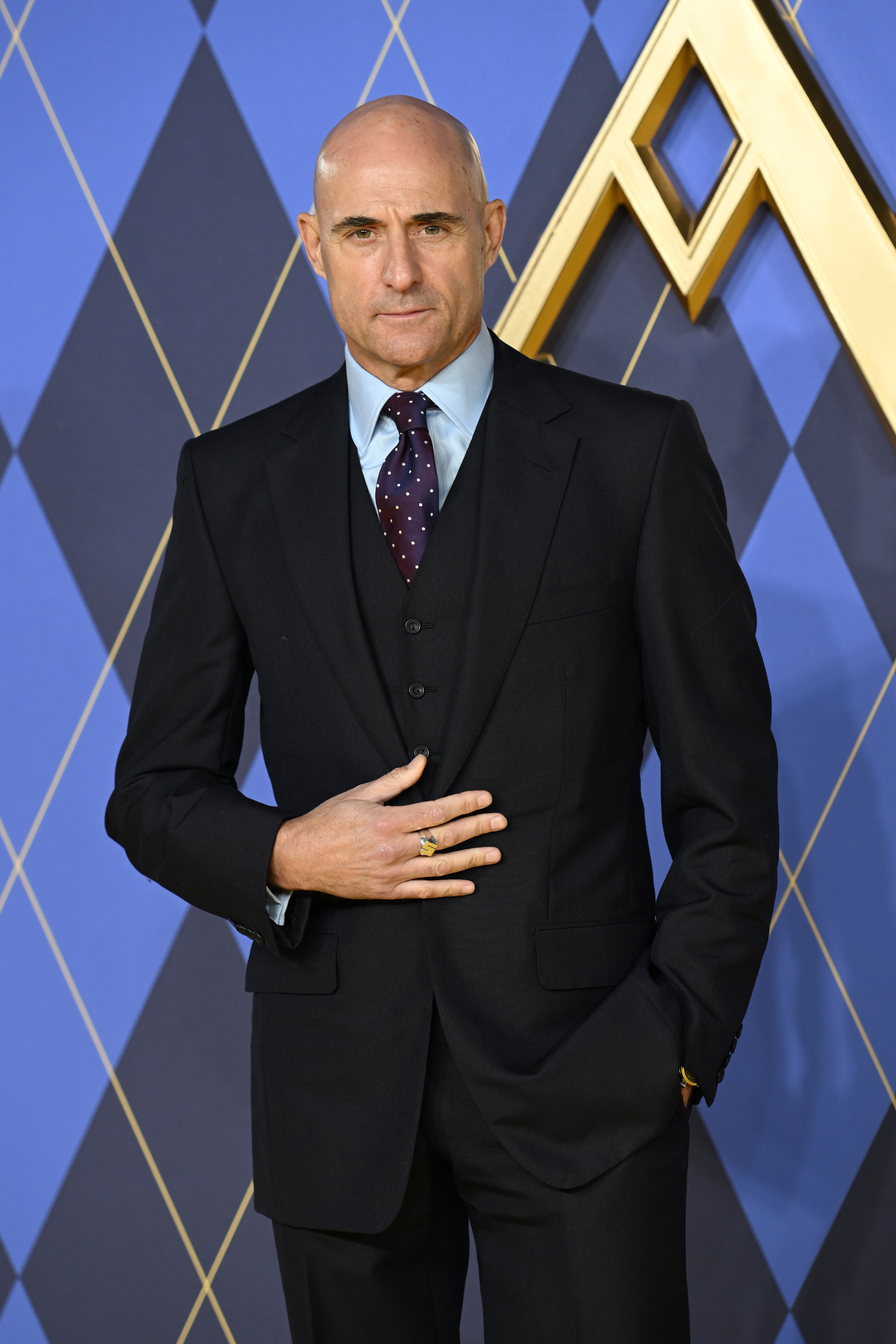 Mark Strong in a sharp suit posing confidently