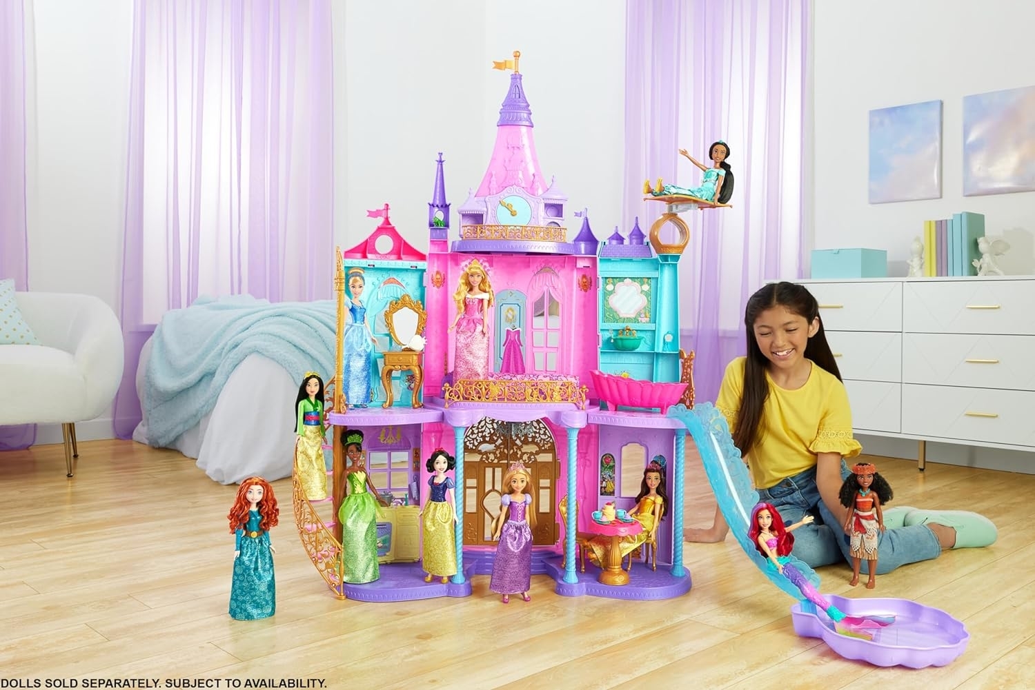 A child plays with a variety of dolls, including figures from Disney's Frozen, in an elaborate toy castle playset