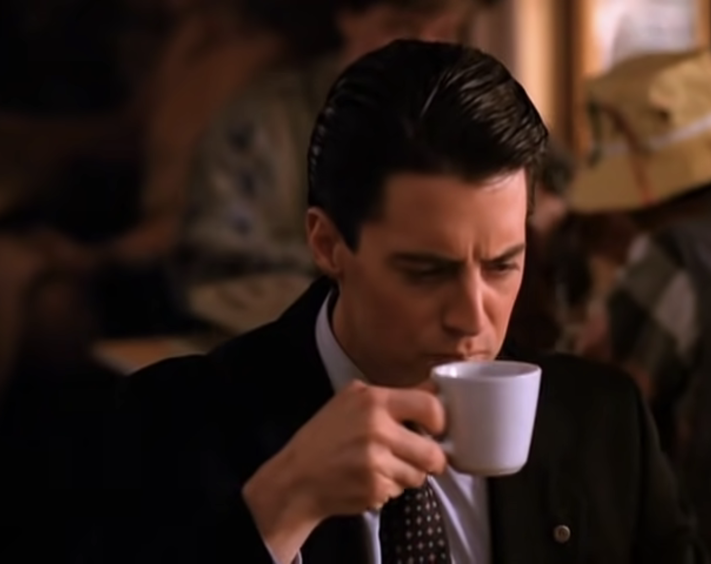 Agent Dale Cooper from Twin Peaks sipping coffee, wearing a black suit with a focused expression