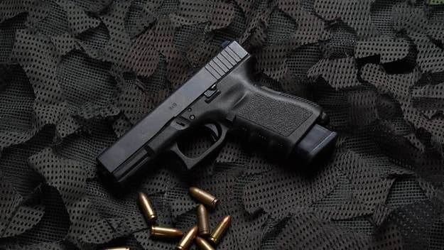 A handgun resting on a textured surface with scattered bullets nearby