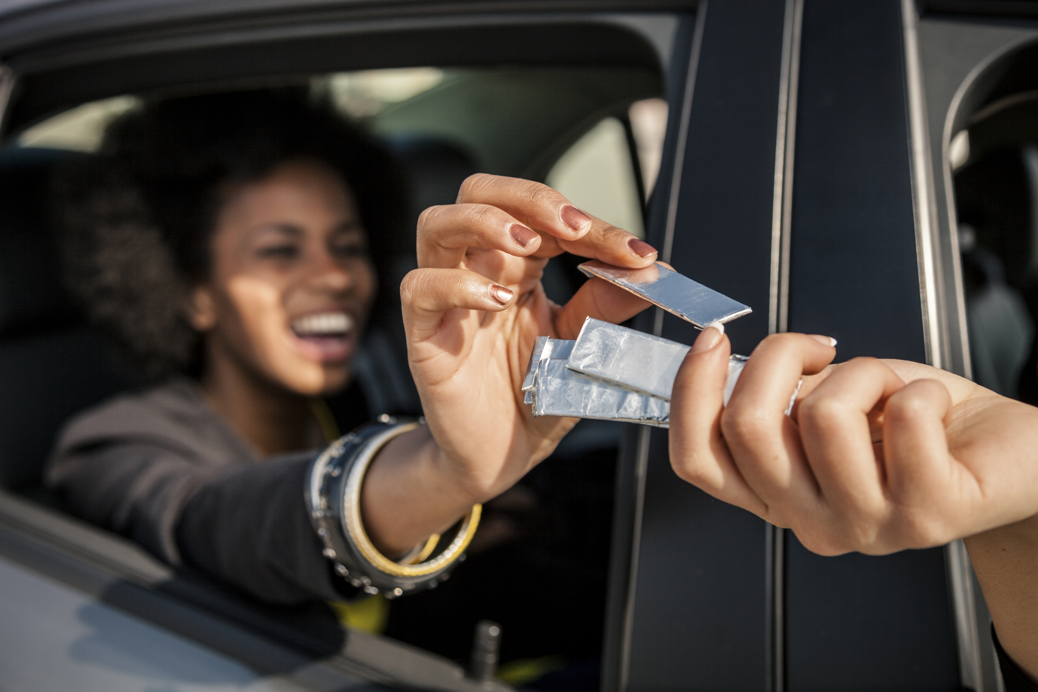 Woman in car receiving chewing gum through the window