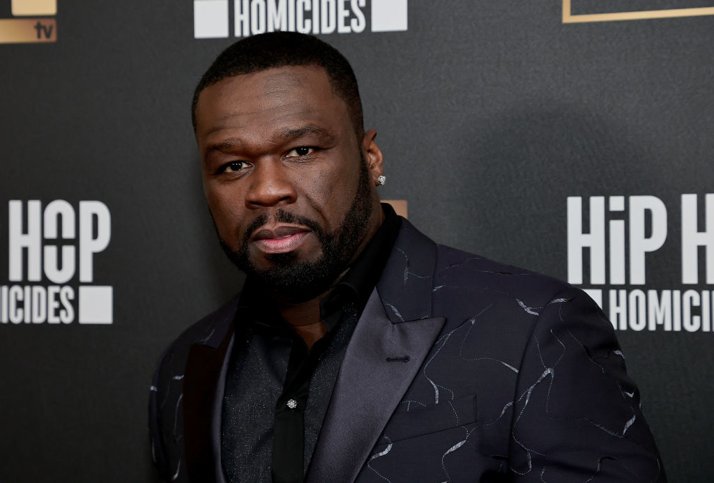 50 Cent wearing a black suit jacket with a subtle pattern, at a Hip Hop Homicides event