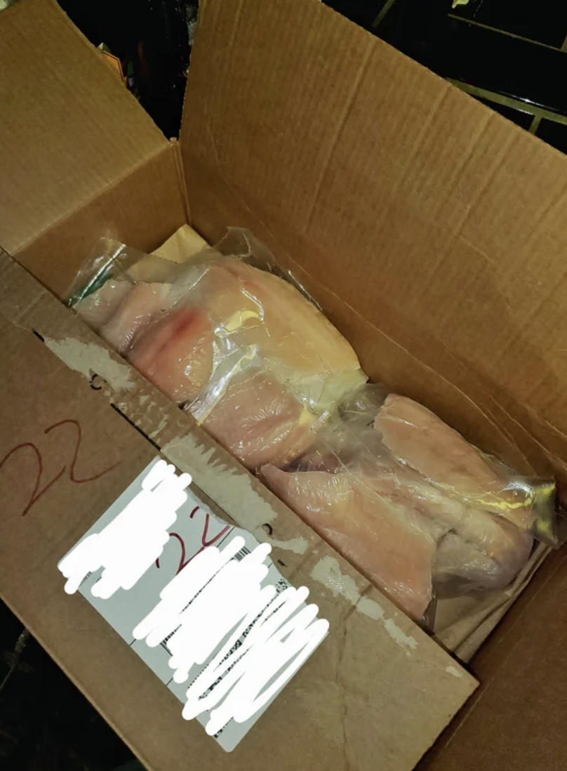 Box filled with packaged chicken breasts, label obscured for privacy