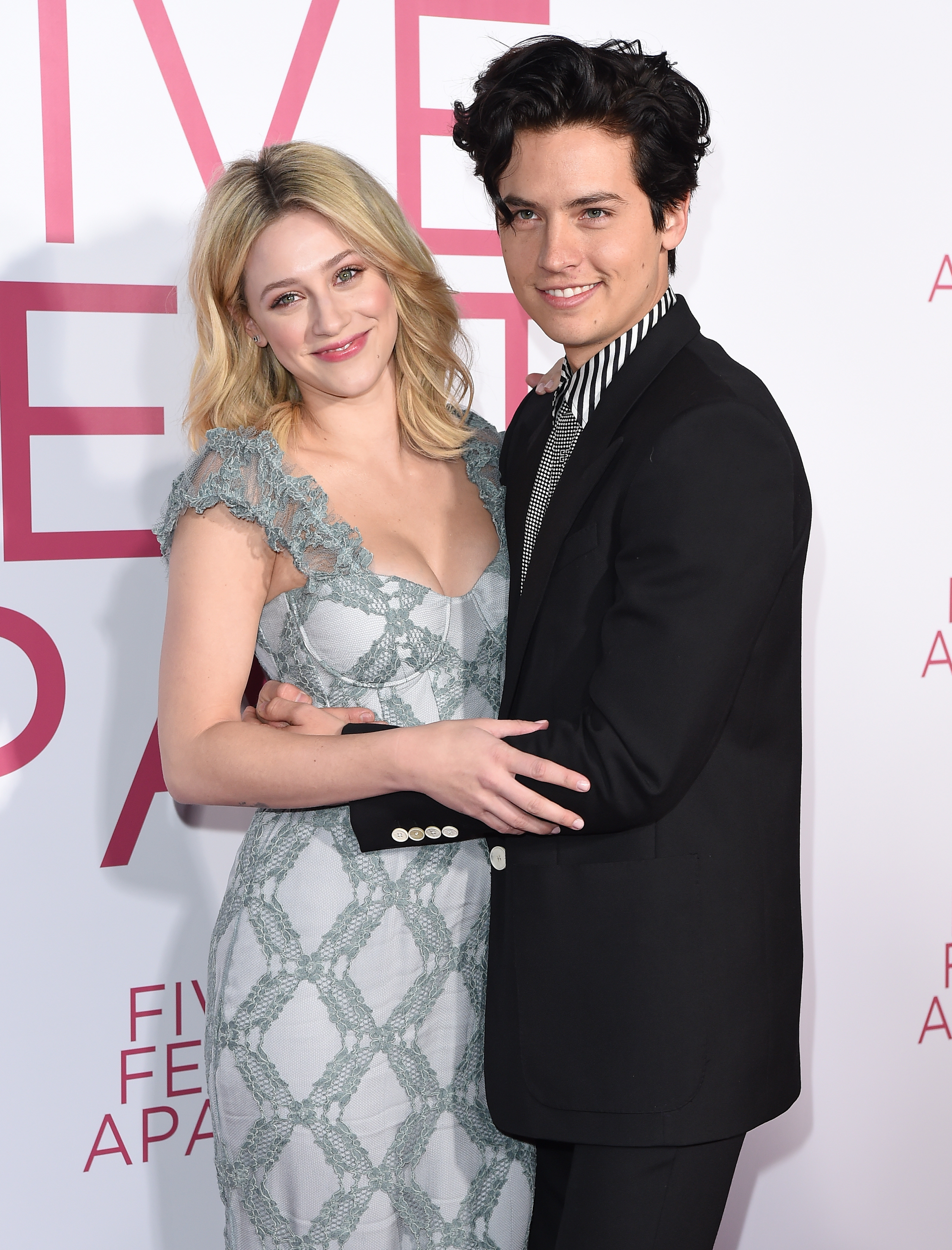 Lili smiling in a ruffled dress, Cole smiling in a black suit with striped collar