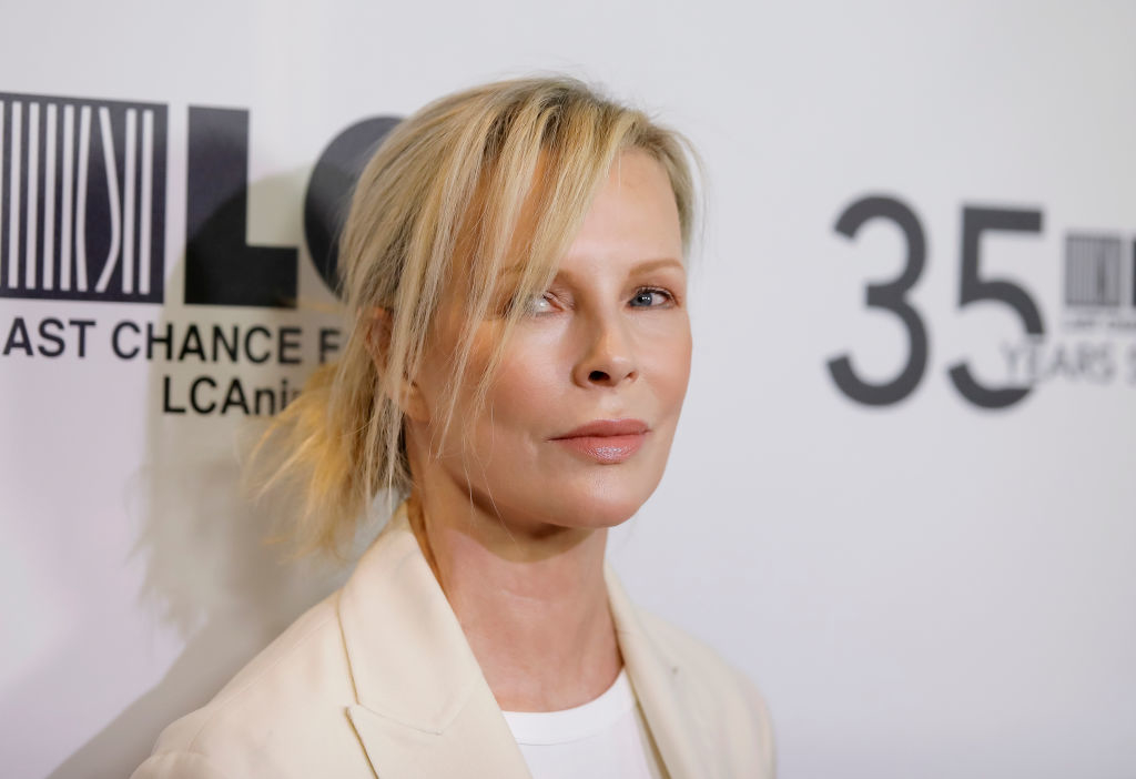 Kim Basinger wearing a blazer, at an event beside a step-and-repeat banner