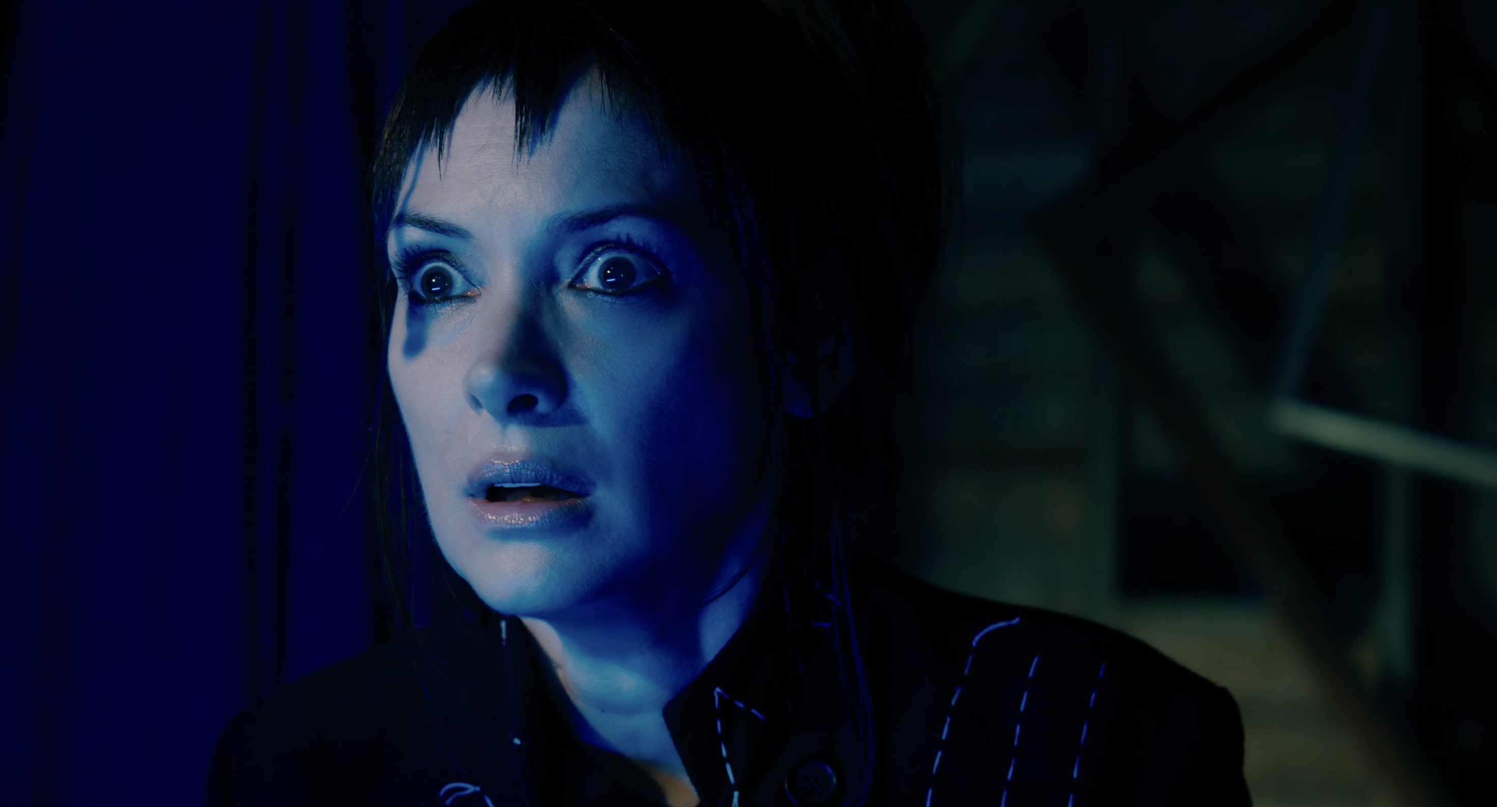 Lydia is in a dark setting, looking surprised or alarmed