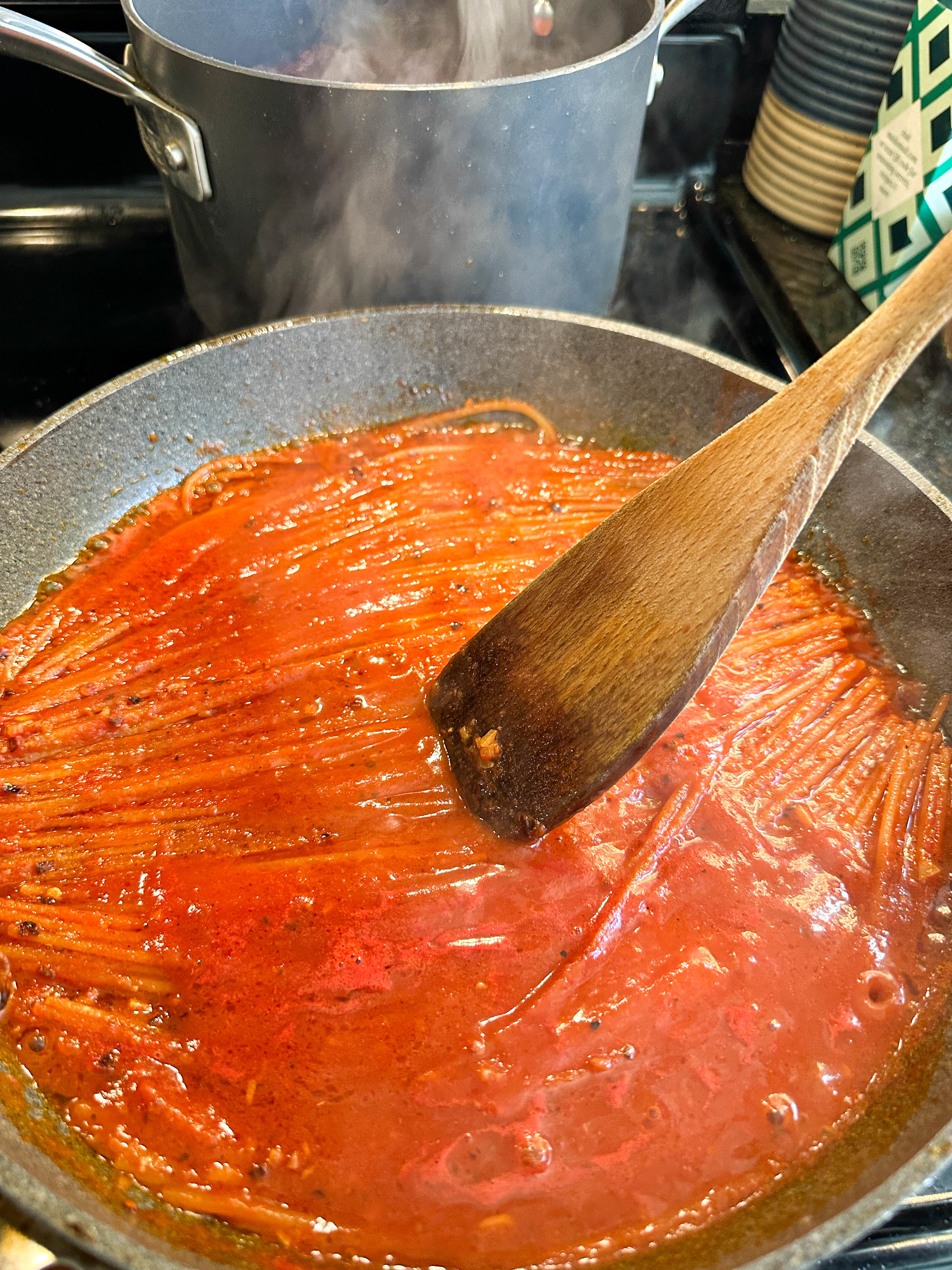 Tomato sauce simmering in a pan with a wooden spoon
