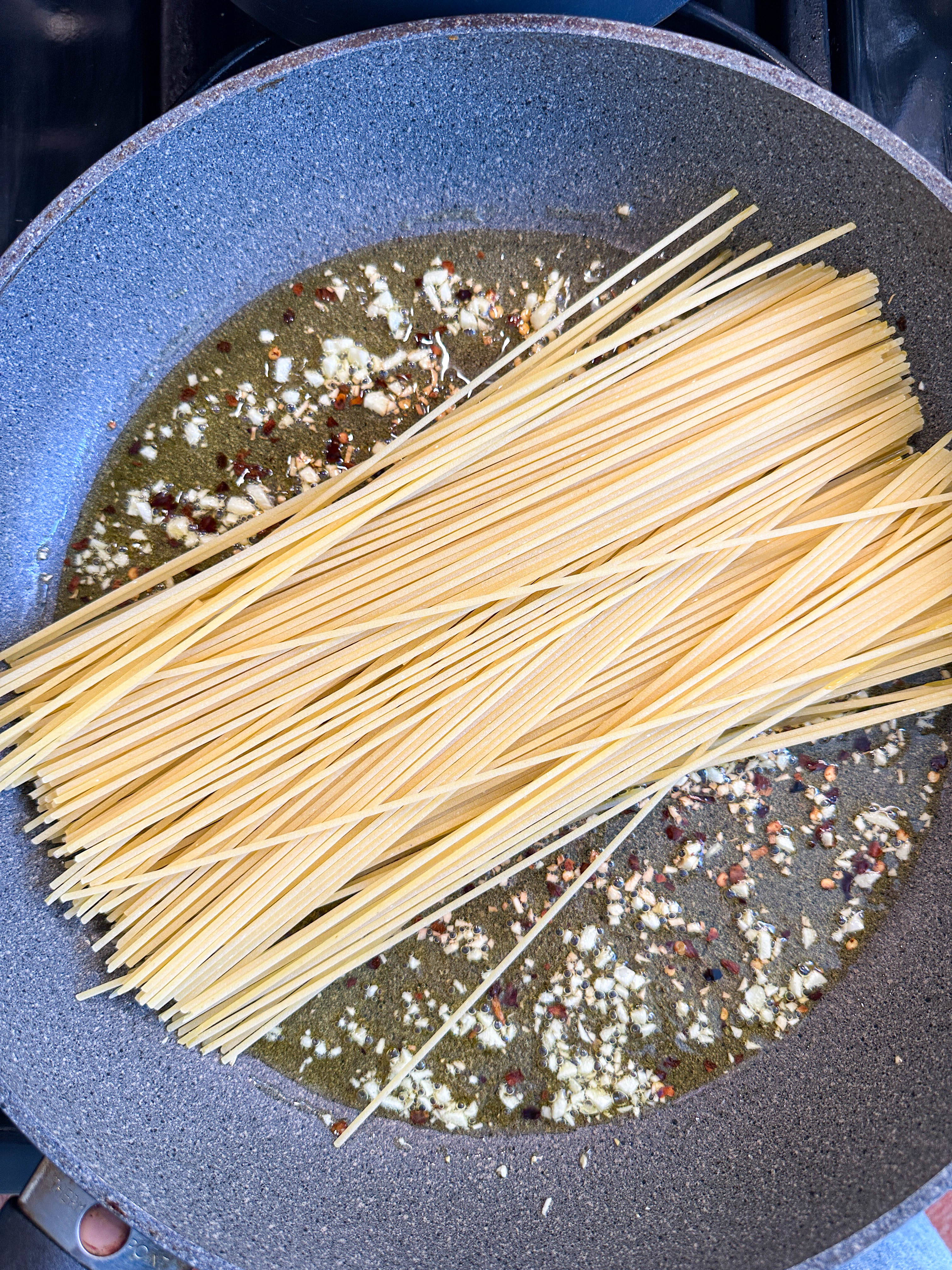 Uncooked spaghetti with spices in a skillet