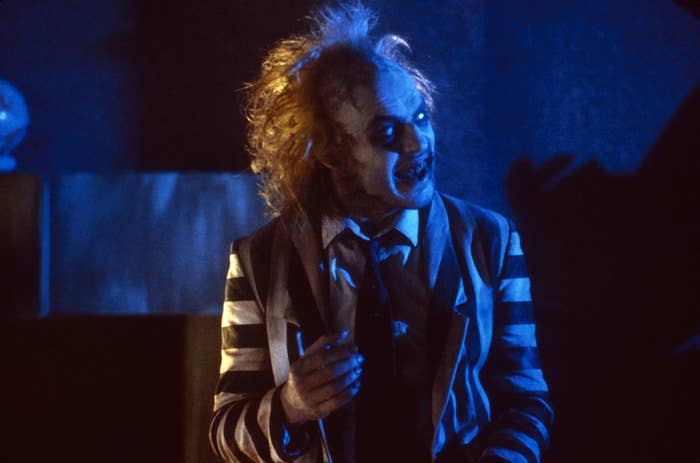 Beetlejuice in striped suit with wild hair, gesturing expressively