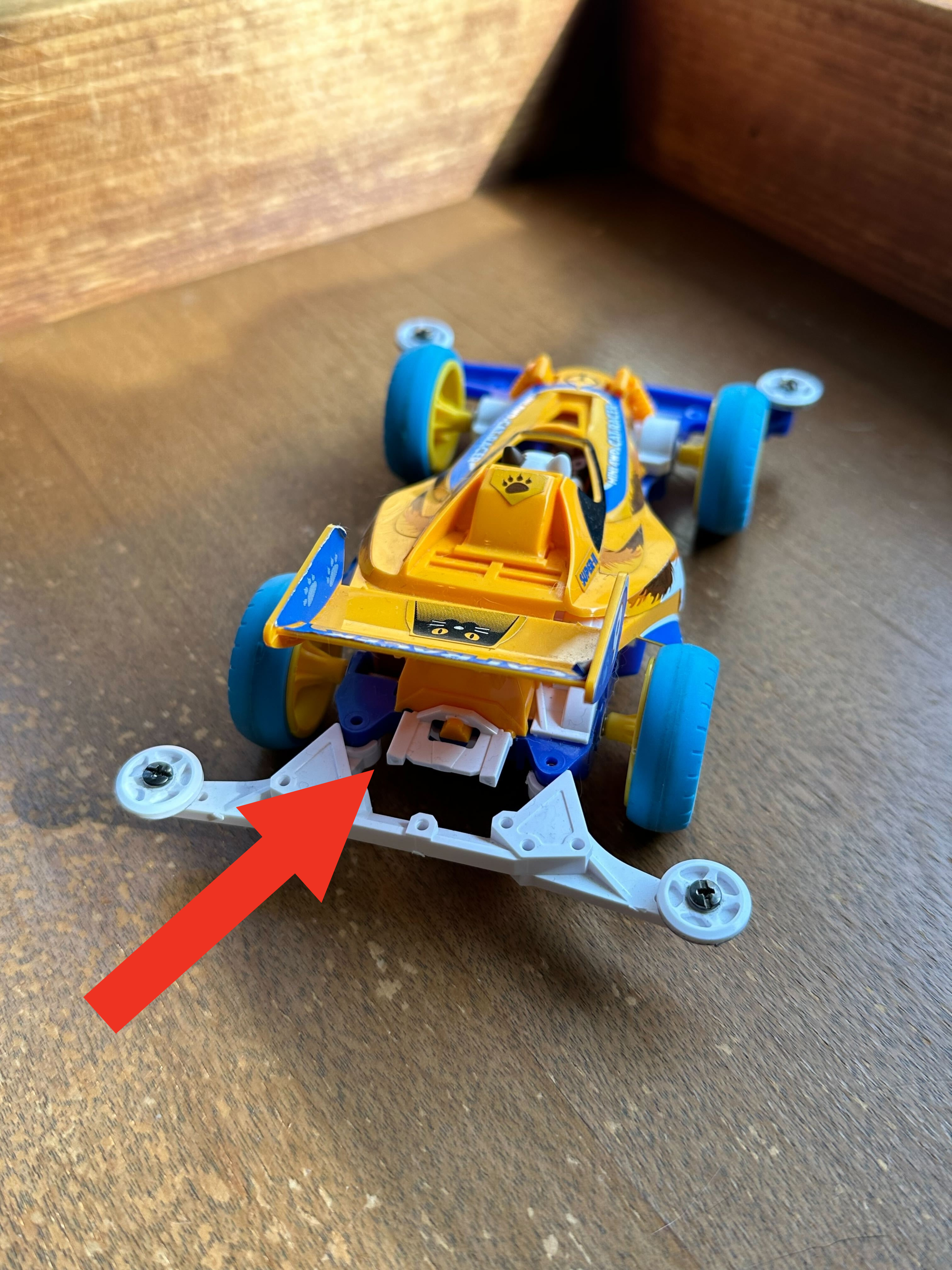 プラスチック製の玩具レースカーが木の表面に置かれています。