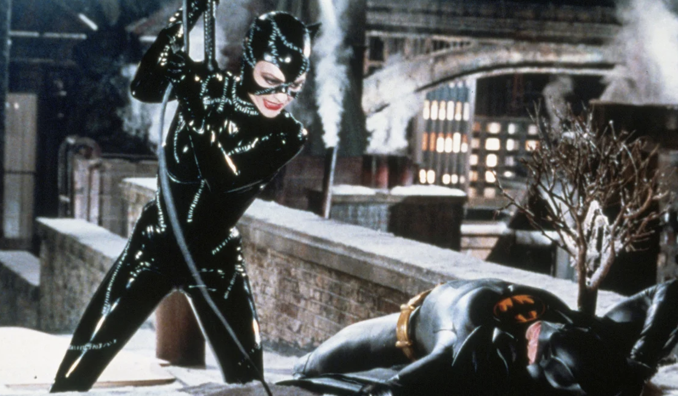 Catwoman poised above downed Batman, both in costumes, portrayed as movie characters