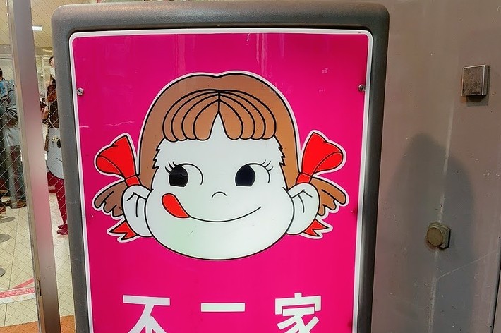 看板には笑顔のアニメキャラクターと「不二家」の文字があります。