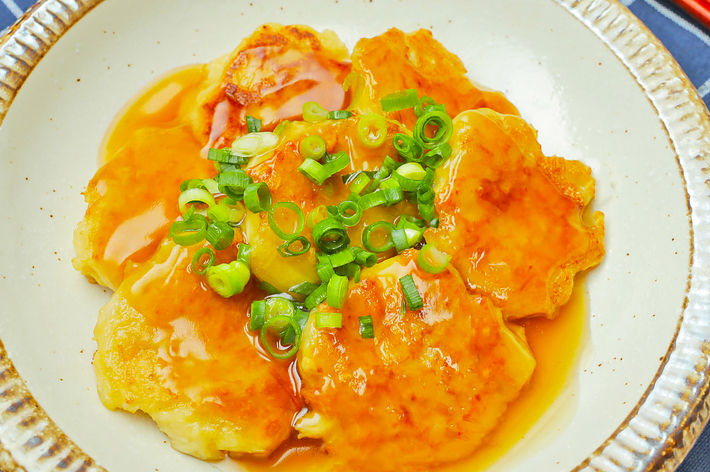 皿に盛られたエビチリにねぎがトッピングされています。