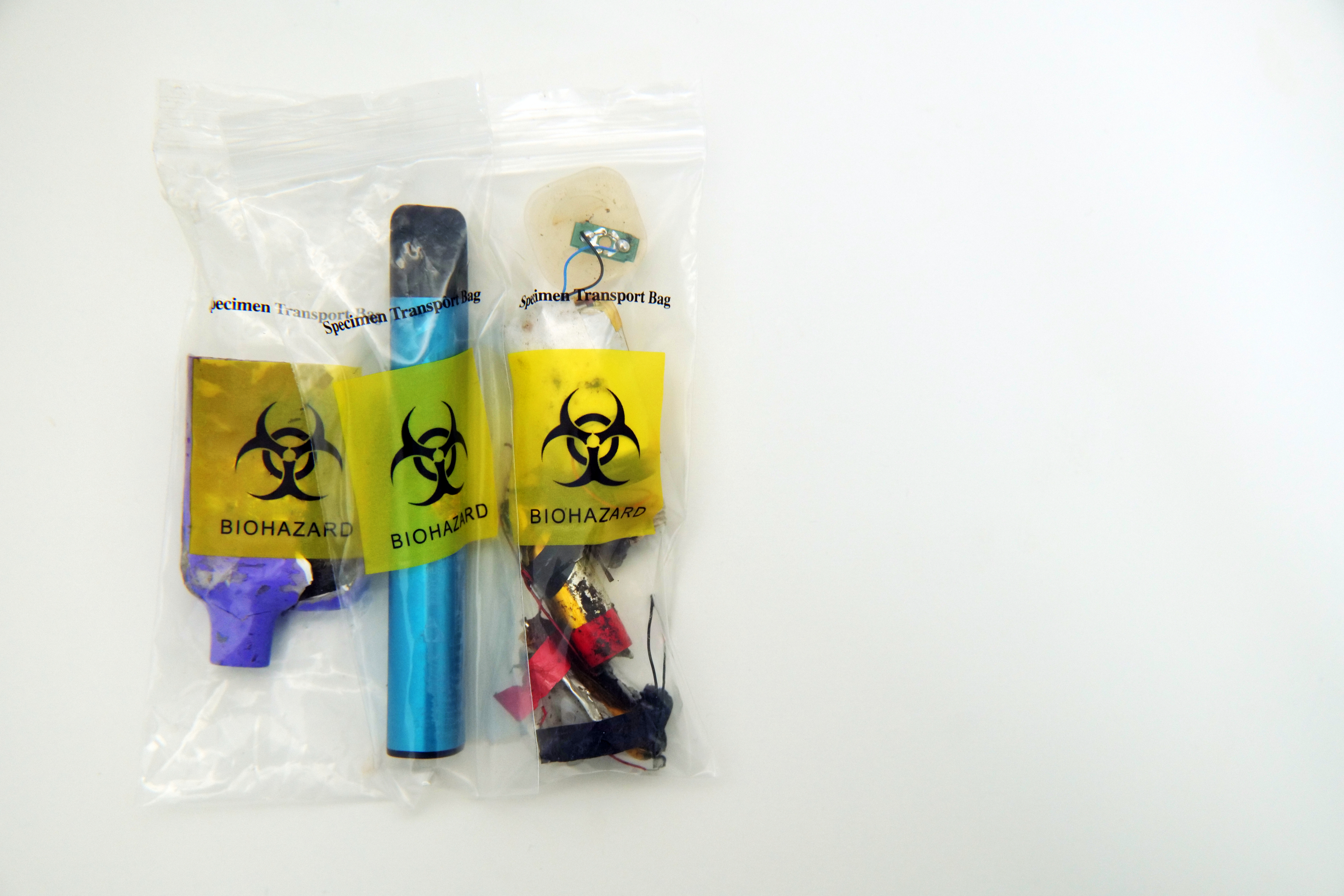 A sealed biohazard bag containing various contaminated items
