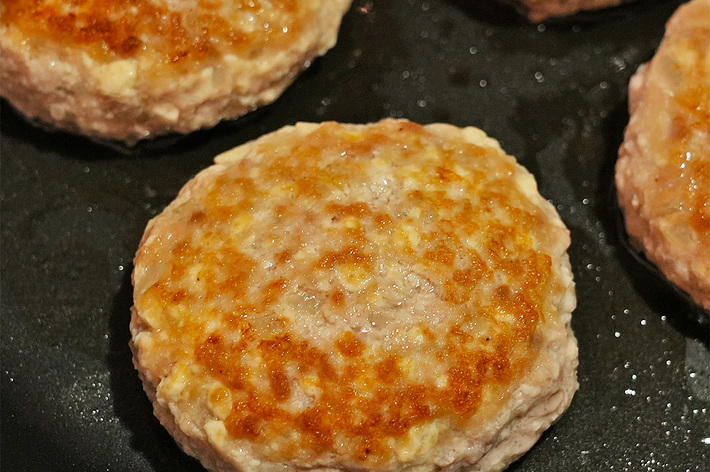 フライパンで調理されている複数のハンバーグパティ。