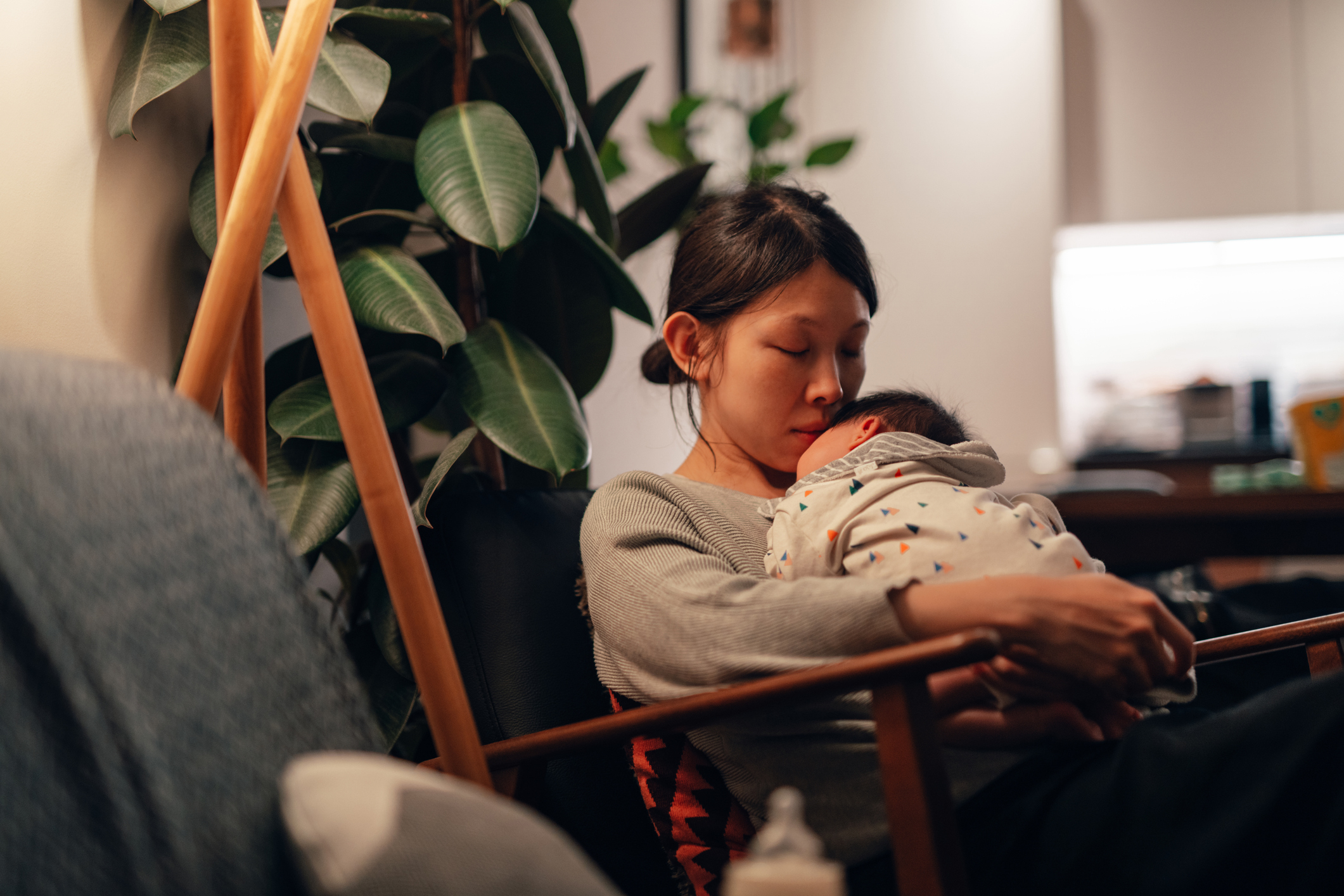 Mother sits cradling and looking at her baby in a warm indoor setting