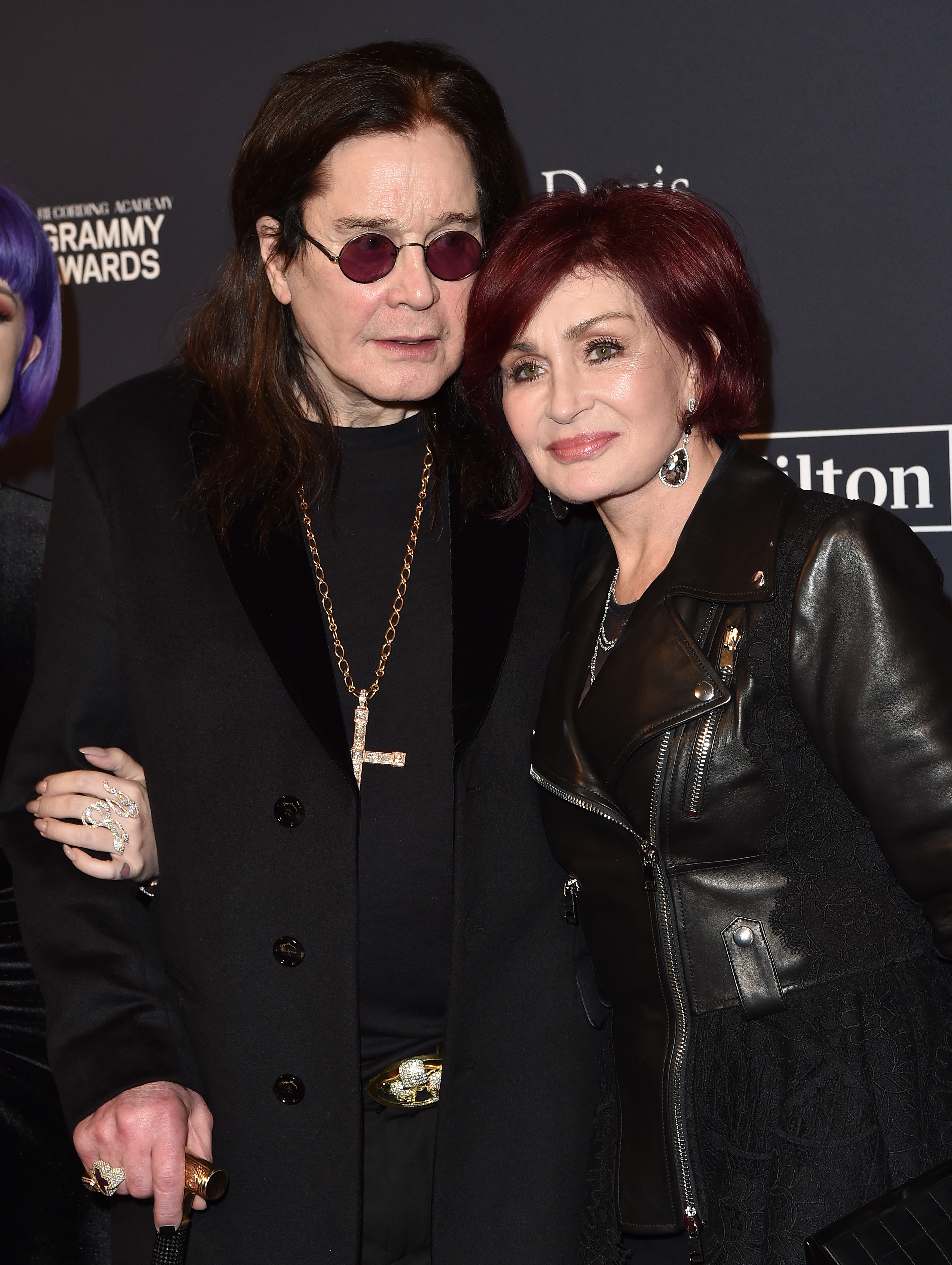 Ozzy Osbourne in a long coat and Sharon Osbourne in a leather jacket, posing at a Grammy event