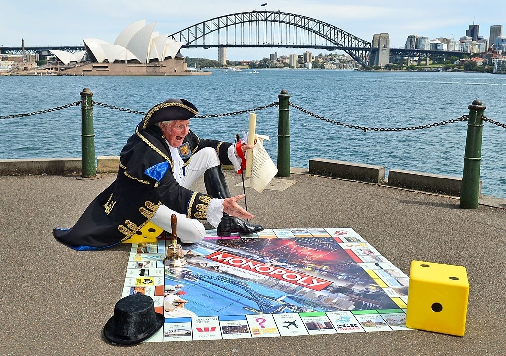 Person in pirate costume playing a giant Monopoly game with Sydney landmarks in the background