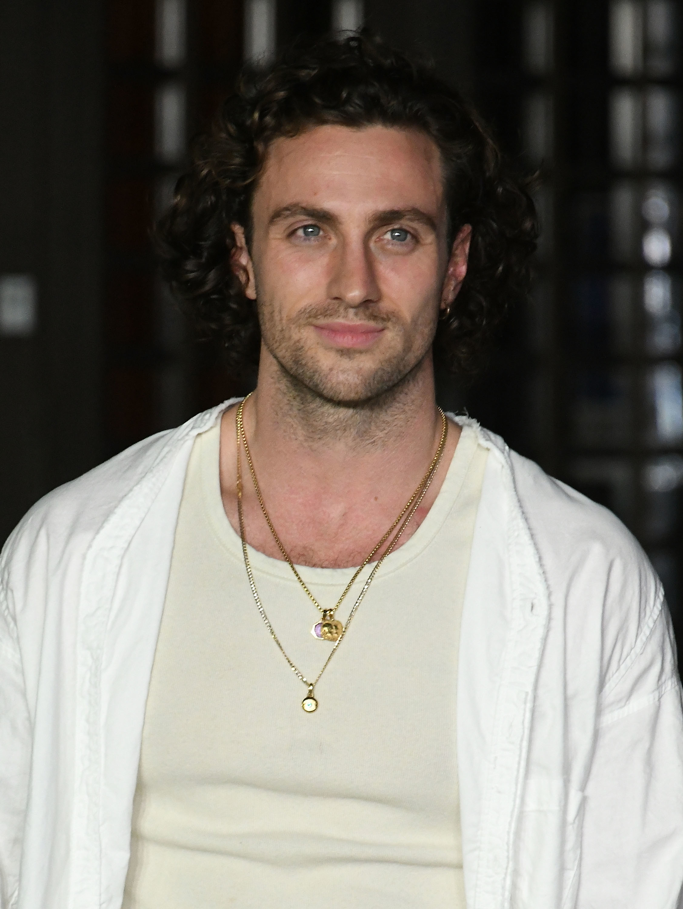 Aarib standing in a T-shirt layered with necklaces, looking directly at the camera