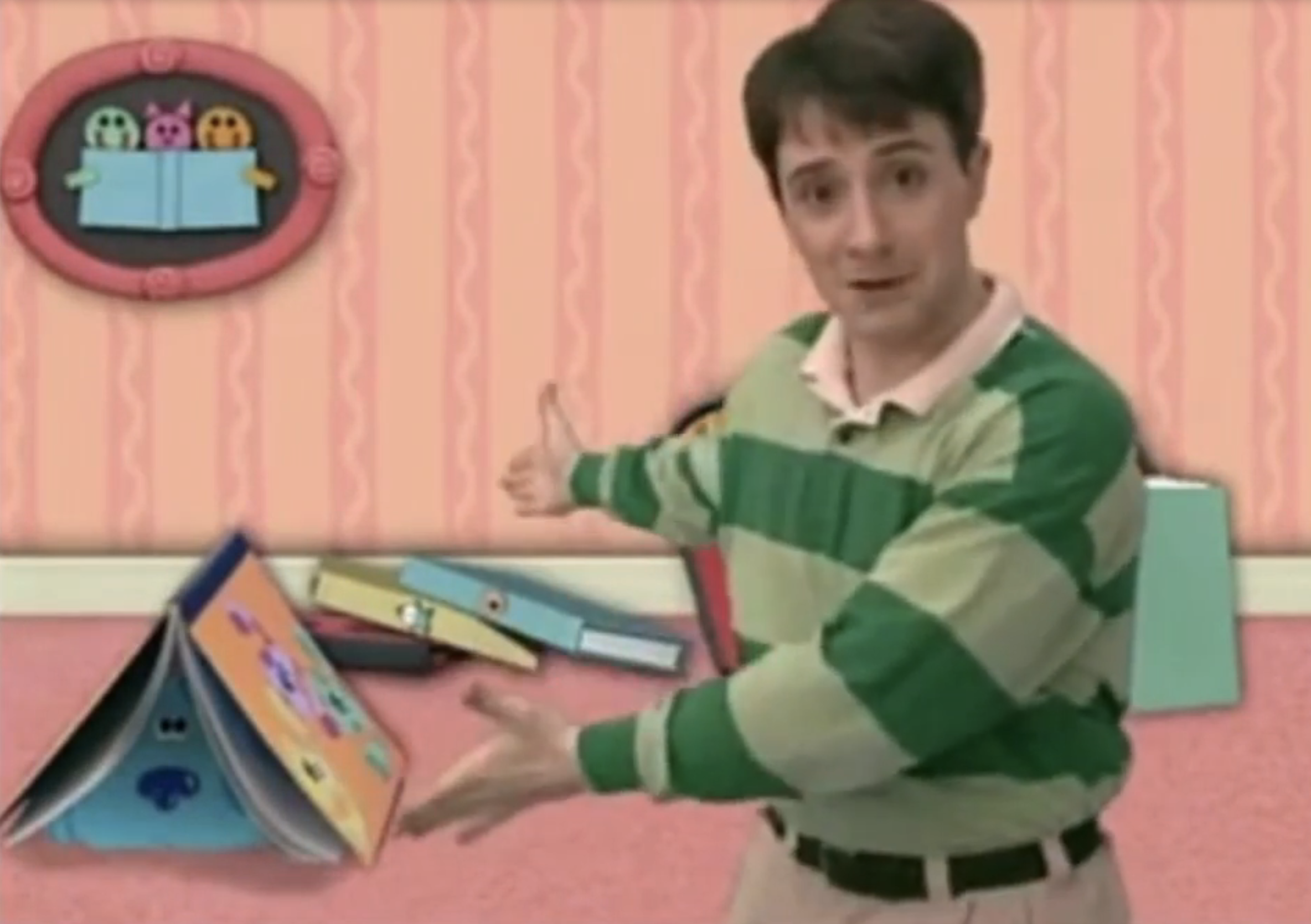 Steve from Blue&#x27;s Clues in a striped shirt gesturing to a fallen stack of animated books
