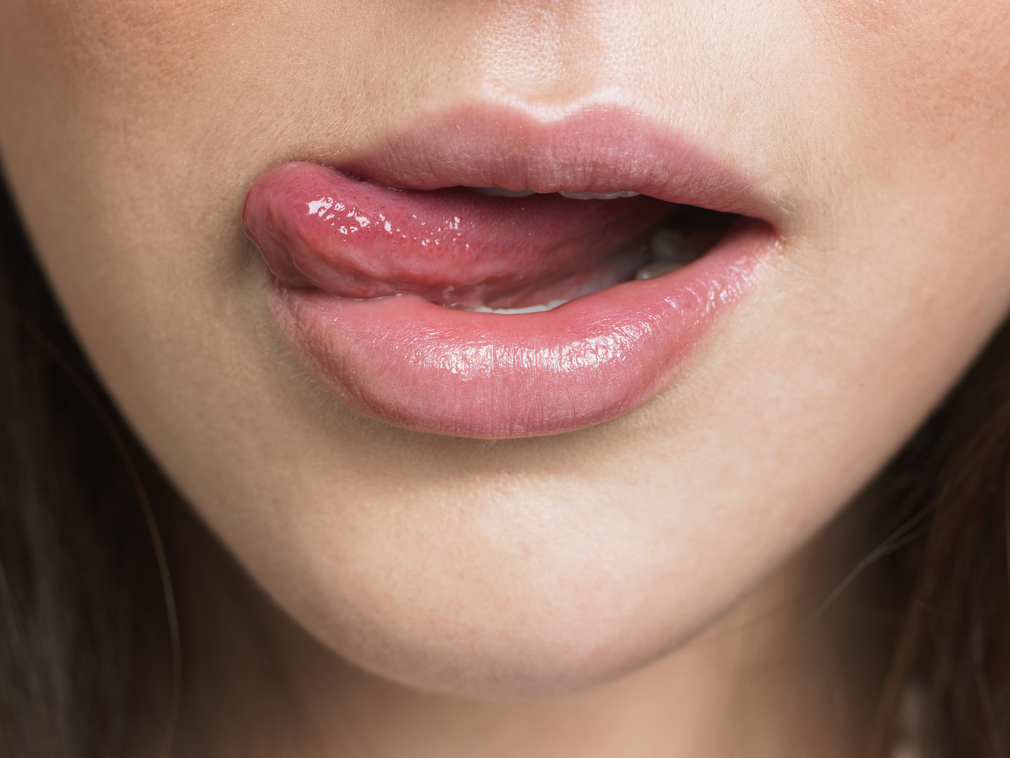 Close-up of a person sticking out their tongue slightly between their lips