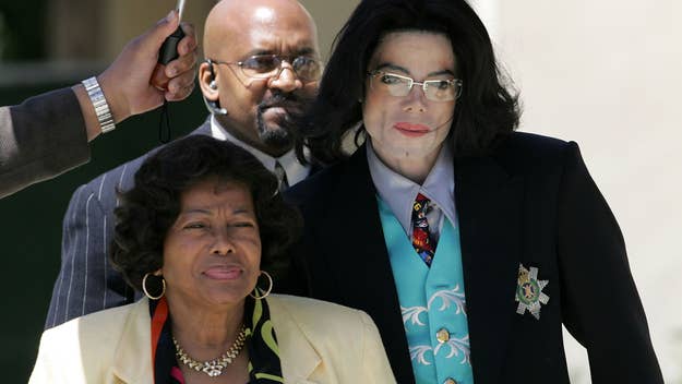 Michael Jackson in a dark suit with a decorative armband, walking alongside two individuals