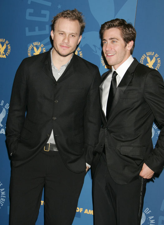 Heath in a buttoned shirt and jacket, and Jake in a black suit and tie at a media event